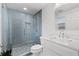 Modern bathroom featuring a glass-enclosed shower with blue tiled walls and a vanity with white countertop at 8136 Honeybee Ln, Tampa, FL 33635