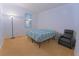 Cozy bedroom with neutral carpet, a queen-sized bed, side table, and a comfortable black recliner chair at 11118 Golden Silence Dr, Riverview, FL 33579
