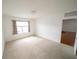 Bright bedroom with neutral carpet, freshly painted white walls, curtains, and a door at 11517 Koti Creek Ln, Thonotosassa, FL 33592