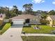 An eye level exterior view of a tan single story home with a manicured green lawn and driveway to a two car garage at 11803 70Th St, Largo, FL 33773