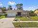 A single story home with a lush green lawn, quaint flower garden and a driveway leading to a two car garage at 11803 70Th St, Largo, FL 33773