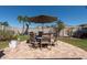 Outdoor dining set with umbrella on a brick patio surrounded by a manicured lawn and lush landscaping at 16331 Treasure Point Dr, Wimauma, FL 33598