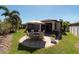 Spacious backyard featuring a stone-paved patio with a dining set and grill, surrounded by lush landscaping at 16331 Treasure Point Dr, Wimauma, FL 33598