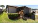 Exterior view of a well-maintained home with a screened-in porch, landscaped yard, and beautiful shrubbery at 16331 Treasure Point Dr, Wimauma, FL 33598