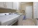 Laundry room featuring tile floors, upper cabinets, and modern washer and dryer units at 16331 Treasure Point Dr, Wimauma, FL 33598