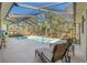 Relaxing backyard screened-in pool featuring lounge chairs, blue skies, and lush landscaping at 16340 Marquis Rd, Brooksville, FL 34614