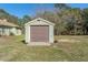 View of shed in yard of property, with garage door and adjacent yard at 16340 Marquis Rd, Brooksville, FL 34614