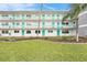 Exterior shot of multi-story condo building featuring turquoise railing, doors, and lush green lawns at 1900 59Th N Ave # 217, St Petersburg, FL 33714