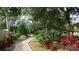 Beautiful garden pathway featuring lush foliage, colorful plants, and mature shade trees at 21537 Clubside Loop, Lutz, FL 33549