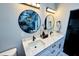 Bright bathroom featuring a double vanity, round mirrors and white cabinets, complemented by marble look floors at 2925 W Dewey St, Tampa, FL 33607