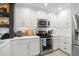Well-lit kitchen featuring white cabinets, marble countertops, and stainless steel appliances at 301 Madeira Cir, Tierra Verde, FL 33715