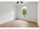 Bright bedroom featuring wood-look flooring and a window overlooking lush palm trees at 30829 Iverson Dr, Wesley Chapel, FL 33543