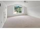 Spacious bedroom with vaulted ceilings, a ceiling fan, plush carpet, and a large window with a green view at 30829 Iverson Dr, Wesley Chapel, FL 33543