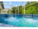 Bubbling hot tub on screened back porch with lush green trees in background at 30829 Iverson Dr, Wesley Chapel, FL 33543