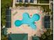 Aerial view of clover-shaped pool with lounge chairs, cabanas and lush landscaping for a resort-style experience at 30829 Iverson Dr, Wesley Chapel, FL 33543