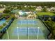 Aerial view of two fenced in tennis courts surrounded by lush trees at 30829 Iverson Dr, Wesley Chapel, FL 33543