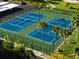 Overhead view of well-maintained blue and green tennis courts surrounded by lush landscaping and a nearby parking area at 670 Island Way # 806, Clearwater Beach, FL 33767