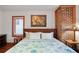 Inviting bedroom featuring paneled walls, a brick pillar, wood floors, an artwork, and a comfortably decorated queen bed at 702 Pass A Grille Way, St Pete Beach, FL 33706