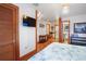 Well-lit bedroom featuring a panelled wall, TV, closet, a bathroom entrance, wood floors, and a comfortable queen bed at 702 Pass A Grille Way, St Pete Beach, FL 33706