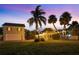 Exterior of home with palm trees and festoon lights strung between the house and garage at 702 Pass A Grille Way, St Pete Beach, FL 33706