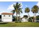 Home exterior with well-manicured lawn, tropical palm trees, and a charming guest house at 702 Pass A Grille Way, St Pete Beach, FL 33706