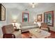 Cozy living room featuring paneled walls, wood floors, comfortable seating, and bright lighting from the windows at 702 Pass A Grille Way, St Pete Beach, FL 33706