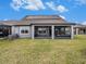 Exterior of home with a well-manicured lawn, covered patio, and solar panels at 7494 Pool Compass Loop, Wesley Chapel, FL 33545