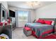 Comfortable bedroom featuring natural lighting, a ceiling fan, gray dresser and red accents at 7494 Pool Compass Loop, Wesley Chapel, FL 33545