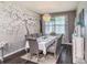 Elegant dining room featuring dark floors, a modern chandelier, and decorative wallpaper with a large window at 7494 Pool Compass Loop, Wesley Chapel, FL 33545
