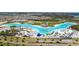 Stunning aerial view of a clear blue lagoon with sandy beaches, an inflatable park, and palm trees at 7494 Pool Compass Loop, Wesley Chapel, FL 33545