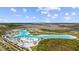 Aerial view of a lagoon with white sand beaches, blue water, inflatable water park, and surrounding community homes at 7494 Pool Compass Loop, Wesley Chapel, FL 33545