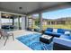 Relax on the covered patio with stylish blue outdoor furniture overlooking the lush green backyard at 7494 Pool Compass Loop, Wesley Chapel, FL 33545