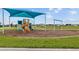 Community playground features a vibrant play structure with a shade cover, swing set, and wood mulch base at 7494 Pool Compass Loop, Wesley Chapel, FL 33545