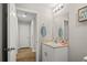 Well-lit bathroom featuring a mirror and a vanity with a sink, next to a doorway at 7580 Freesia Trce, Wesley Chapel, FL 33545