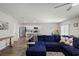 Spacious living room with a large blue sectional couch, adjacent to the kitchen and dining area with bar stool seating at 7580 Freesia Trce, Wesley Chapel, FL 33545