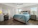 Bright main bedroom featuring a large bed, a ceiling fan, and a vanity area with natural light from two windows at 7580 Freesia Trce, Wesley Chapel, FL 33545