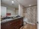 Bathroom showcasing double sinks, dark wood cabinets, granite countertop, and tiled shower at 7922 Spring Valley Dr, Tampa, FL 33615