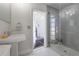 Bright modern bathroom with tile flooring, tiled shower, pedestal sink, and access to the outdoors at 7922 Spring Valley Dr, Tampa, FL 33615