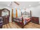 Bedroom featuring a decorative bed frame, hardwood floors, and natural lighting from windows at 8012 Savannah Sunset Ln, Tampa, FL 33615