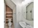 Cozy half bath with a wood accent wall, pedestal sink, and round mirror offering a modern design at 8306 Red Spruce Ave, Riverview, FL 33578