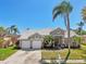 Charming single-story home with a tile roof, mature palm trees, and a well-manicured lawn at 954 Cobblestone Ln, Tarpon Springs, FL 34688