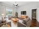Staged living room showcasing hardwood floors, neutral furniture, and an expansive window offering a pool view at 954 Cobblestone Ln, Tarpon Springs, FL 34688