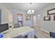 A home office features a white desk, modern chandelier, and view into other rooms at 10072 Sage Creek Dr, Ruskin, FL 33573