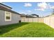 A grassy backyard with a white privacy fence and view of the screened in pool at 1571 Montgomery Bell Rd, Wesley Chapel, FL 33543