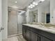 Modern bathroom with double sinks, granite counters, and a tiled walk-in shower with glass door at 1571 Montgomery Bell Rd, Wesley Chapel, FL 33543