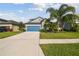 Beautiful single-Gathering home with lush green lawn, mature palm trees, and a driveway leading to the blue garage at 1571 Montgomery Bell Rd, Wesley Chapel, FL 33543