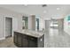 Open-concept kitchen with dark cabinets, an island, and wood-look tile that seamlessly connects to the living area at 1571 Montgomery Bell Rd, Wesley Chapel, FL 33543