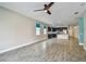 Open-plan living area with kitchen view, tile floors, ceiling fan, and bright windows at 1571 Montgomery Bell Rd, Wesley Chapel, FL 33543
