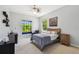 Serene bedroom featuring a bed with a blue comforter, two windows, a reading chair, and neutral decor at 17003 Madres De Avila, Tampa, FL 33613