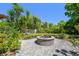 Outdoor patio featuring a charming stone fire pit and lush tropical landscaping at 17003 Madres De Avila, Tampa, FL 33613